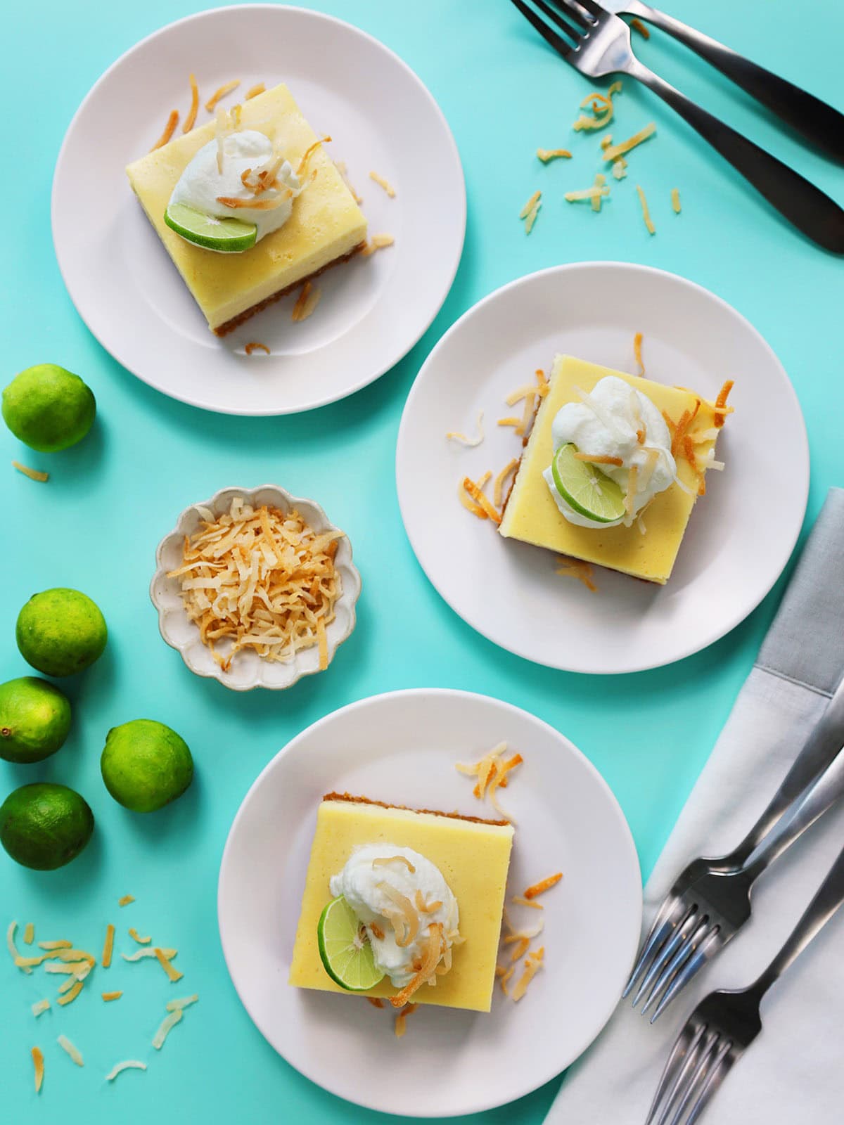 Three plates of key lime pie bars with coconut on white plates.