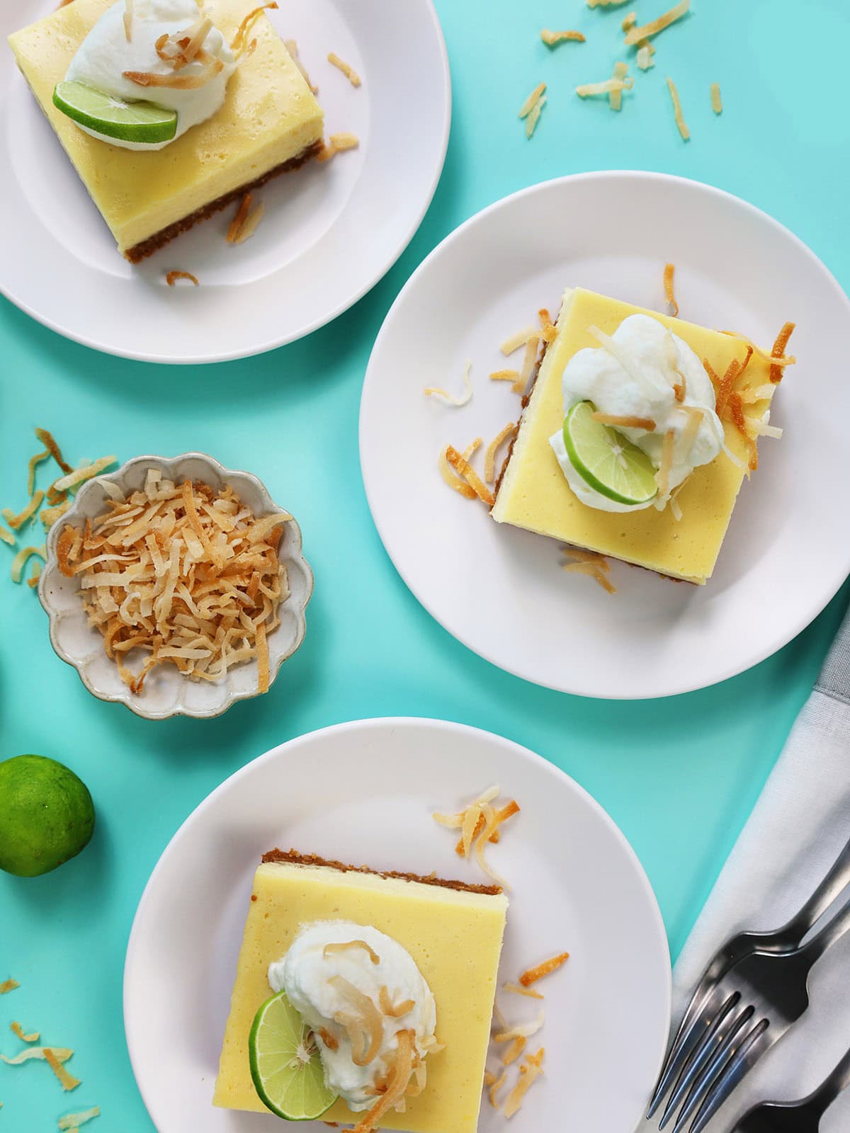 Close up overhead of squares of key lime pie bars with coconut and cream on top.