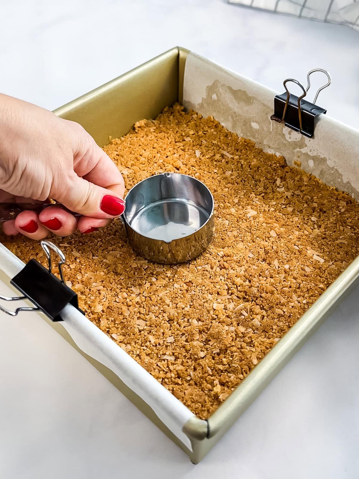 Pressing graham cracker and coconut cookie crust into pan for lime bars.