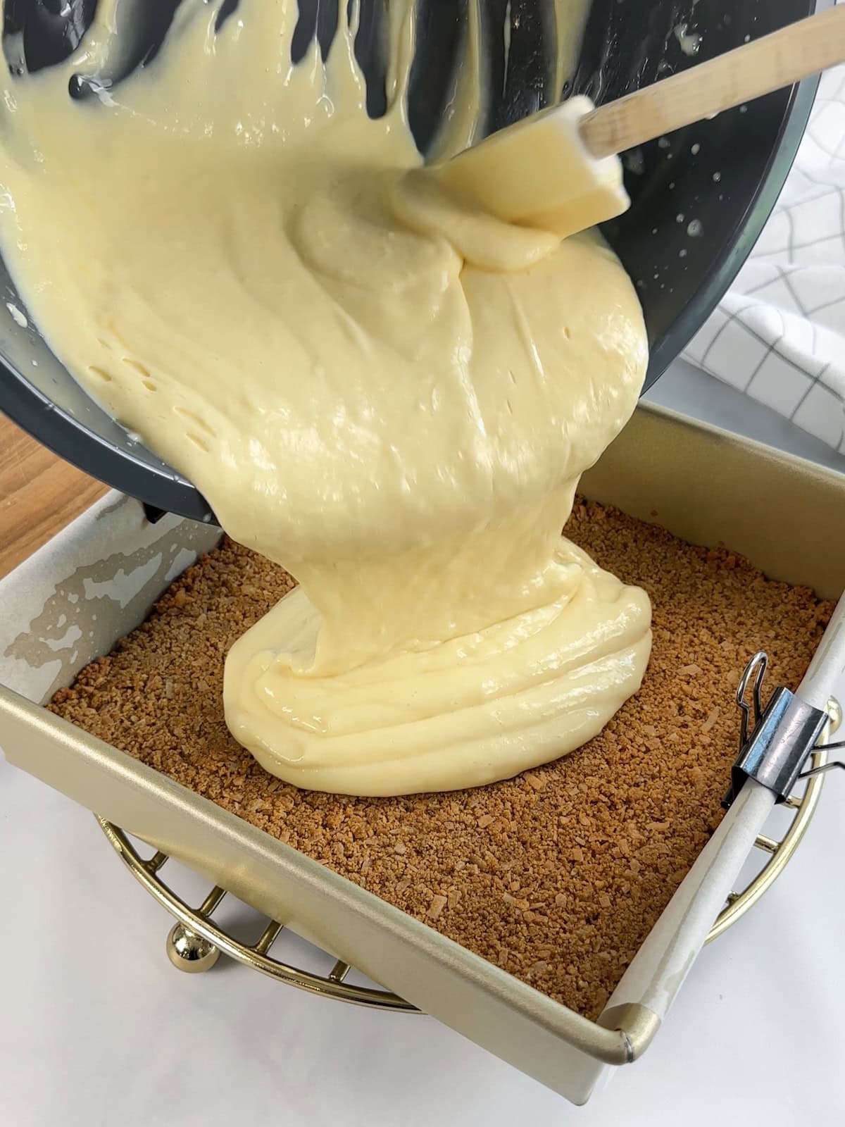 Pouring whipped lime bar filling into baked coconut graham cracker crust in pan.