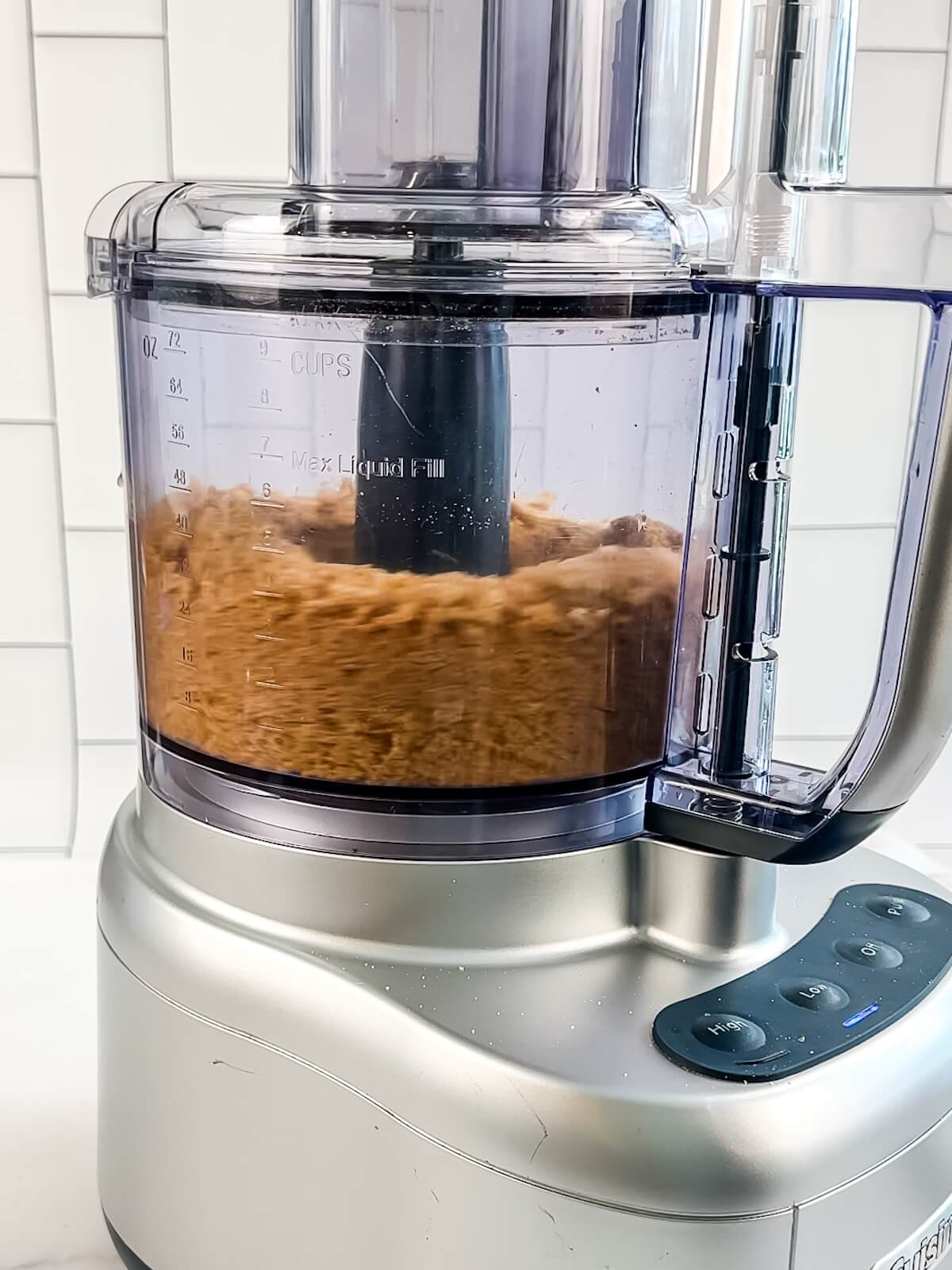 Blending ground graham crackers and melted butter with sugar in a food processor for cookie pie crust.