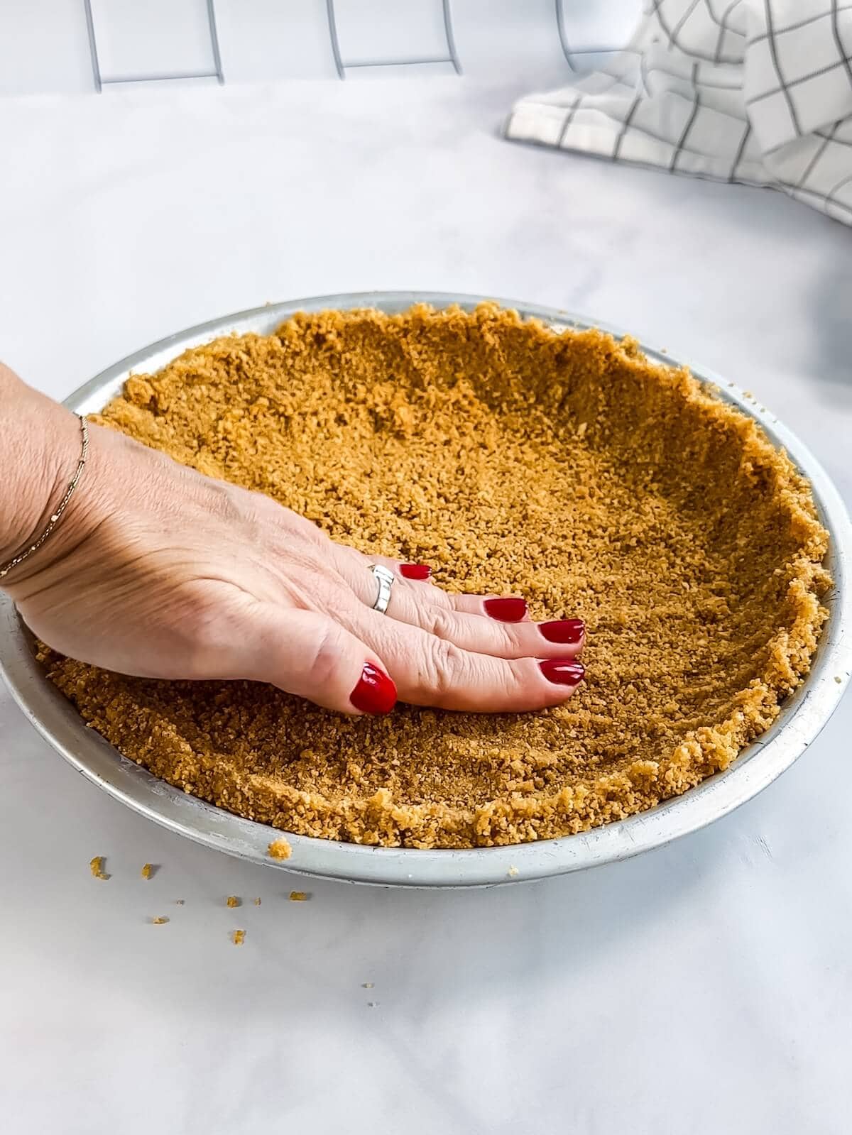 Pressing graham cracker crust into a pie tin. Making sure it's even up the sides.