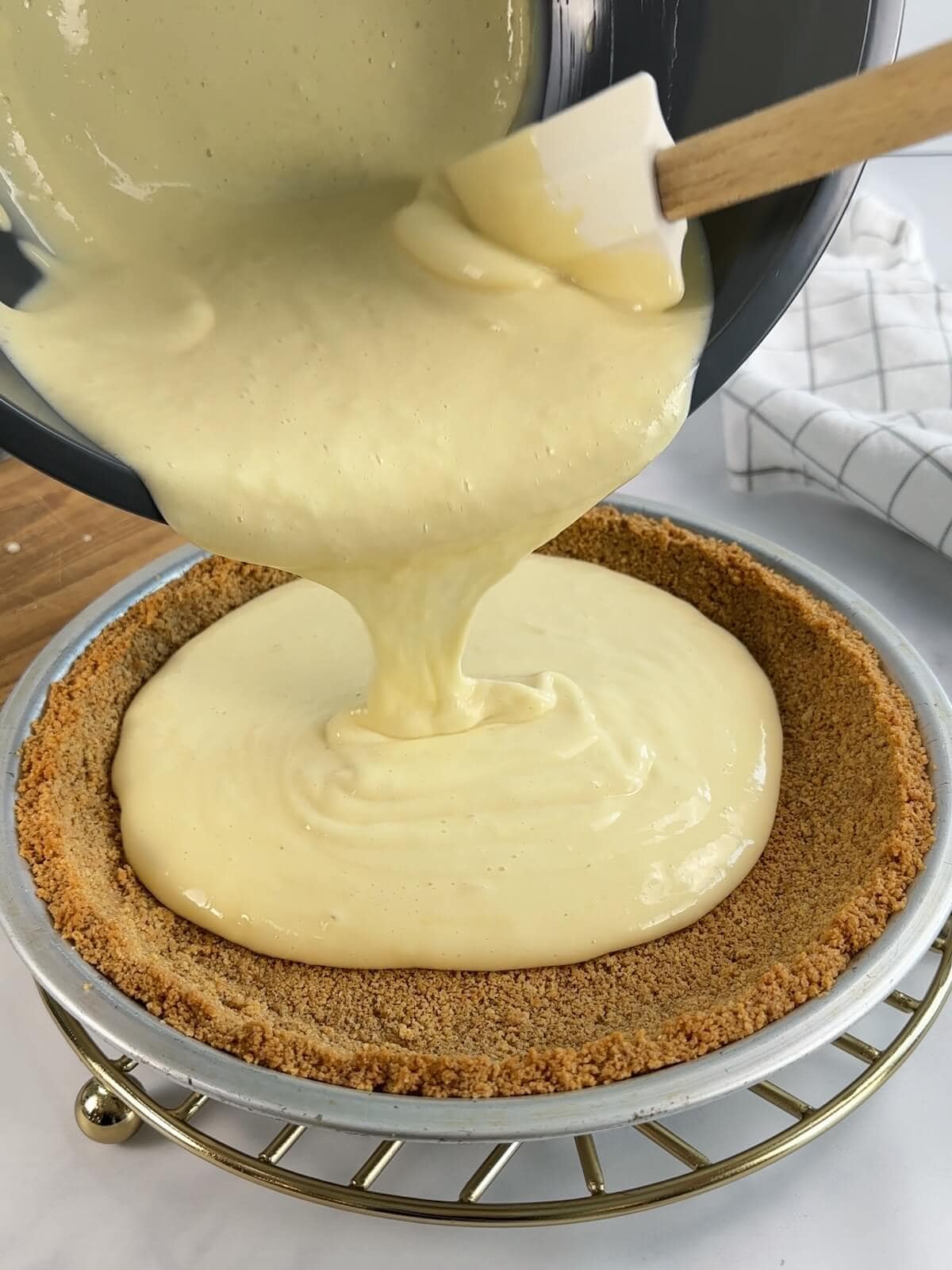 Pouring key lime pie filling into baked crust before baking again. Scrape everything from the bowl.