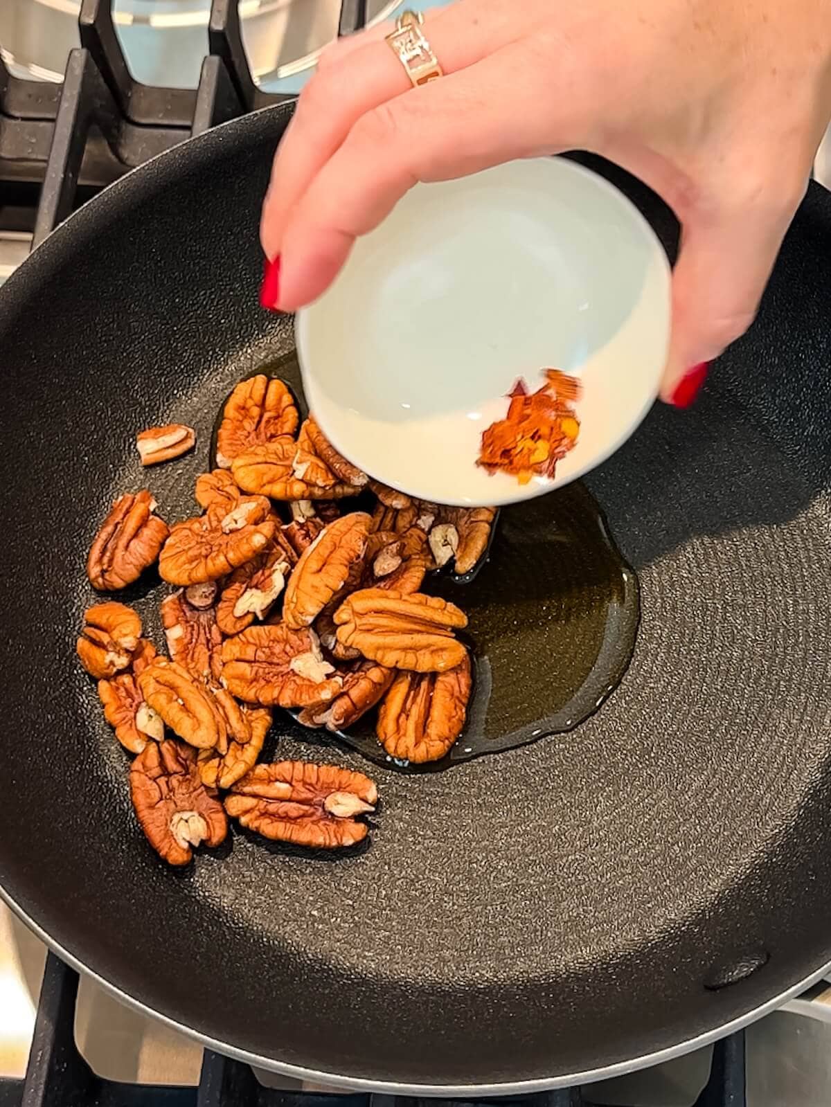 Cook pecans, maple syrup, and chili flakes in a skillet for candied nuts.