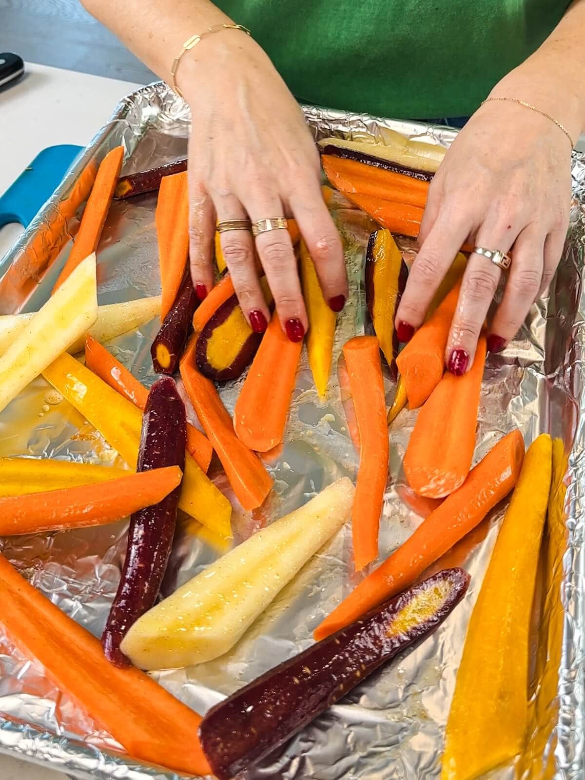 spreading carrots evenly on a lined baking sheet to roast for a warm salad.