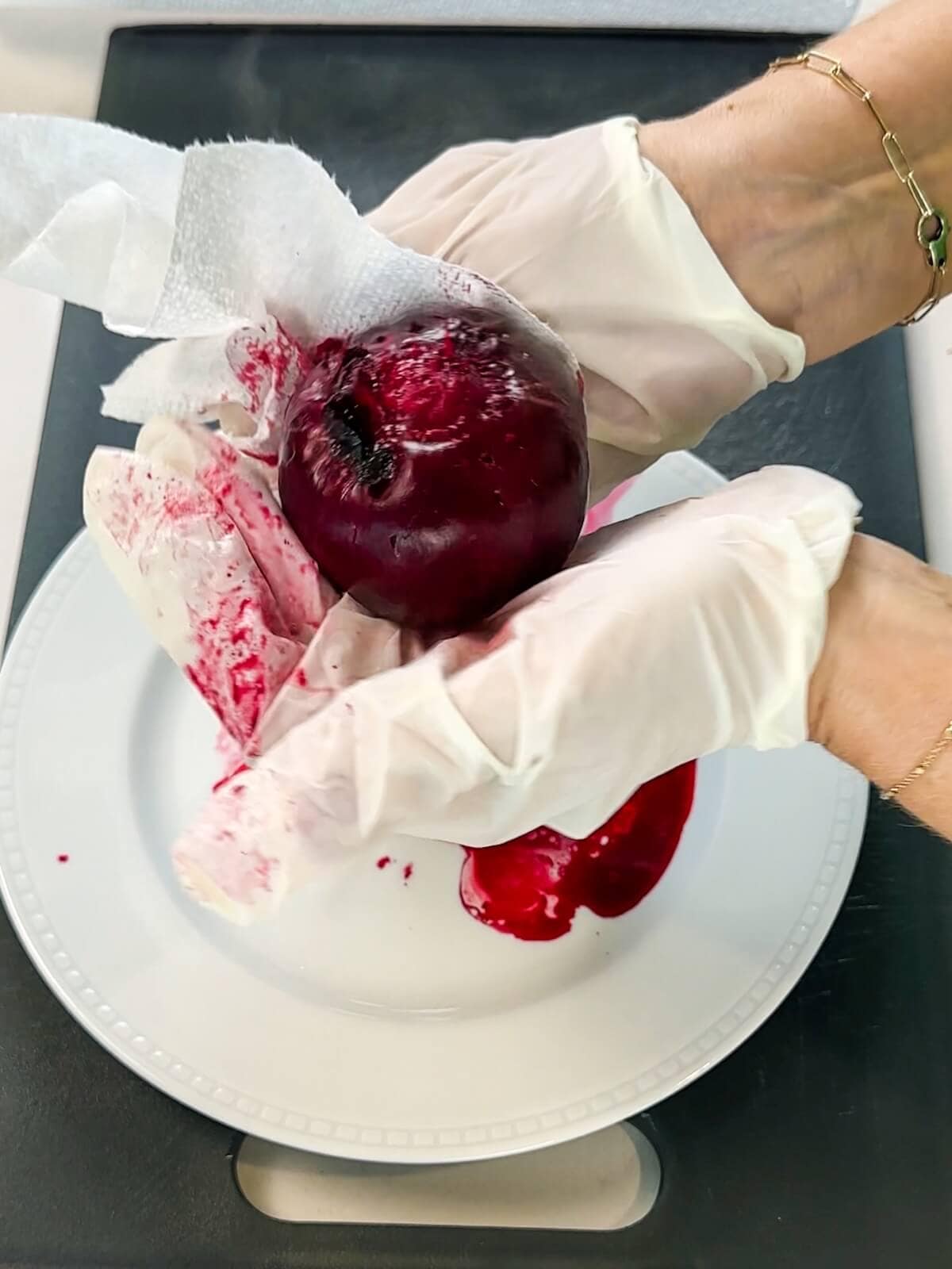 Use gloved hands and a paper towel to pull skin from cooked beets.