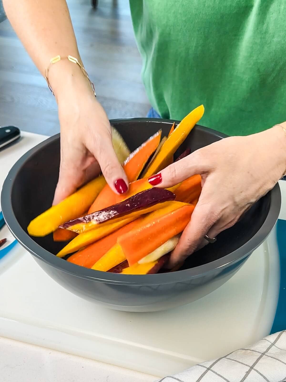Tossing cut carrots in vinaigrette in a bowl before roasting.