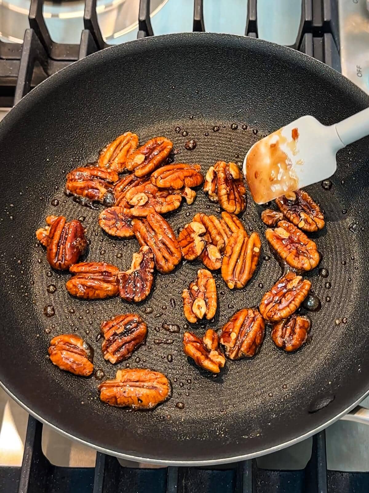 Cooking pecans in maple syrup until caramelized.