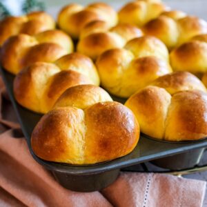 Sweet potato dinner rolls in a muffin pan.