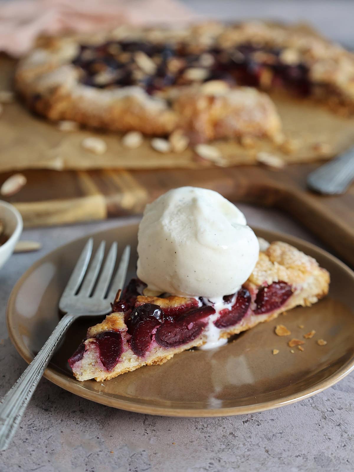 A slice of cherry galette with a big scoop of vanilla ice cream.