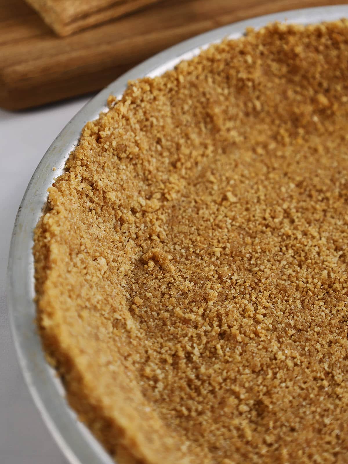Close up of a graham cracker pie crust in a silver pie pan.