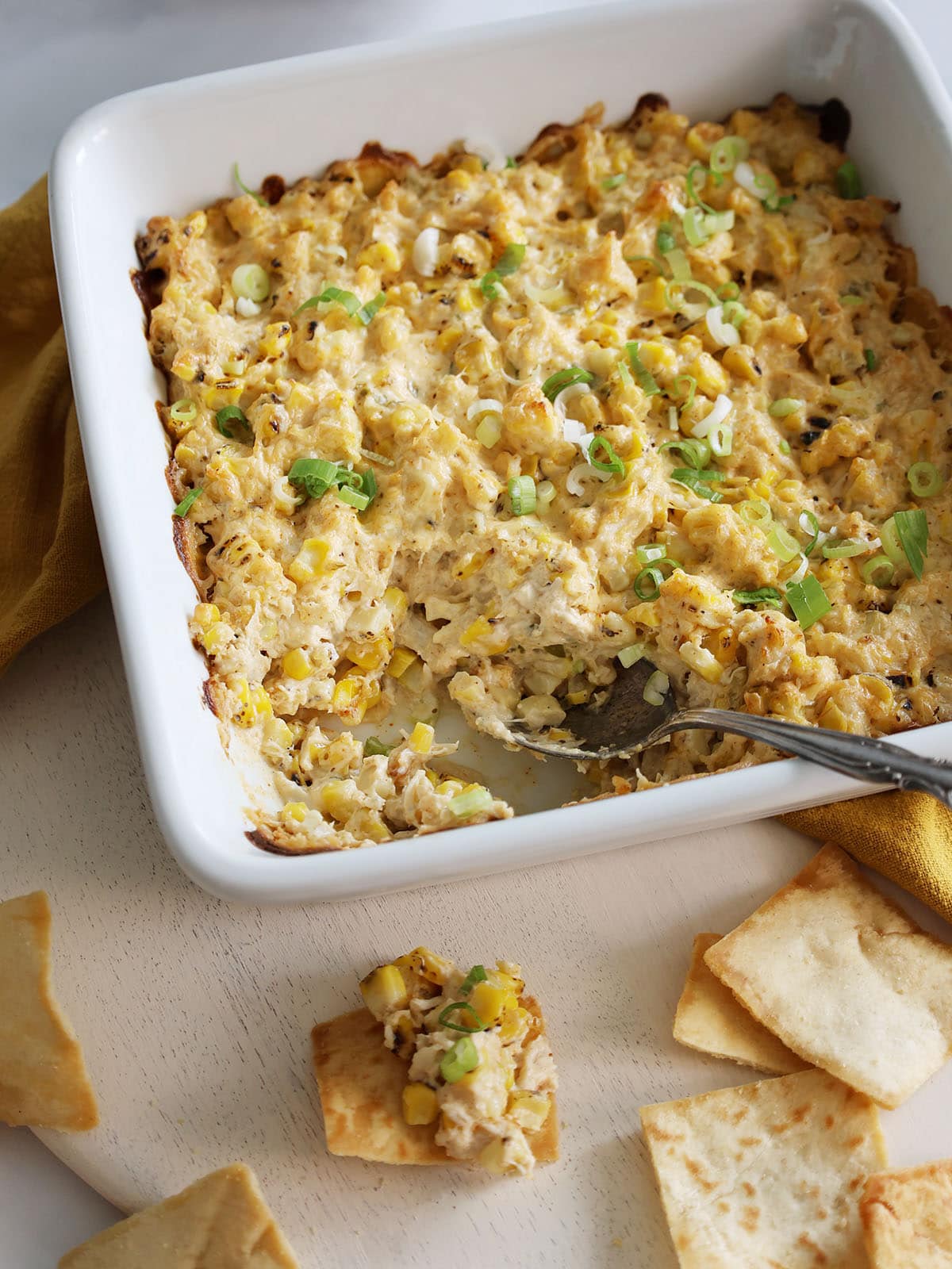 Baked crab dip in a ceramic pan with a few portions removed.