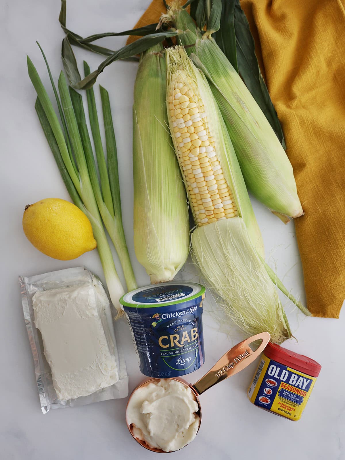 Ingredients needed for hot crab dip including crab, mayonnaise, old bay, cream cheese, lemon, scallions, corn.