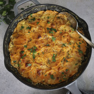 Top view of a skillet filled with scalloped sweet potatoes.