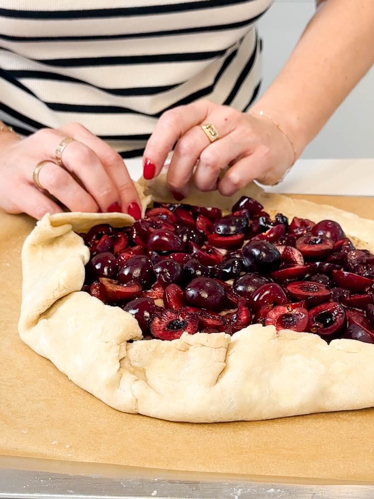 Hand folding pie dough around cherry and almond filling.