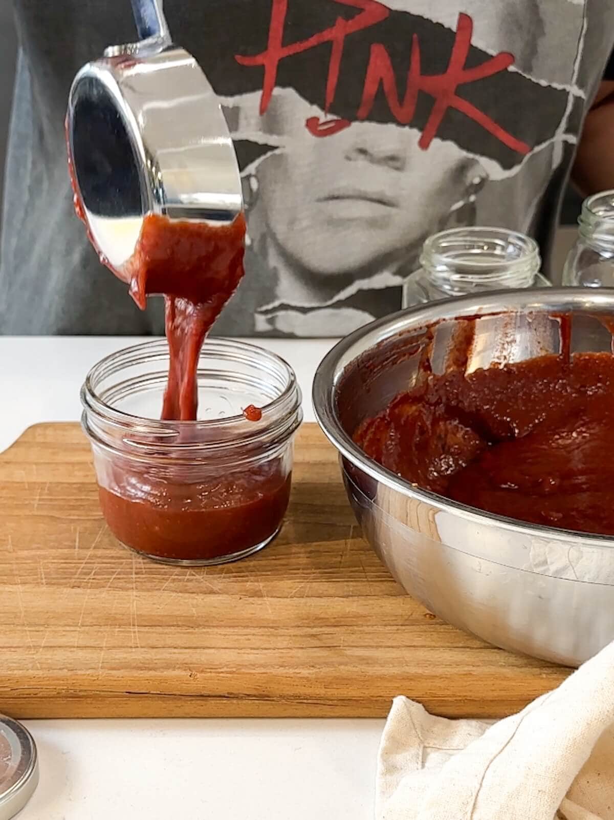 Pouring cranberry bbq sauce into a small jar.