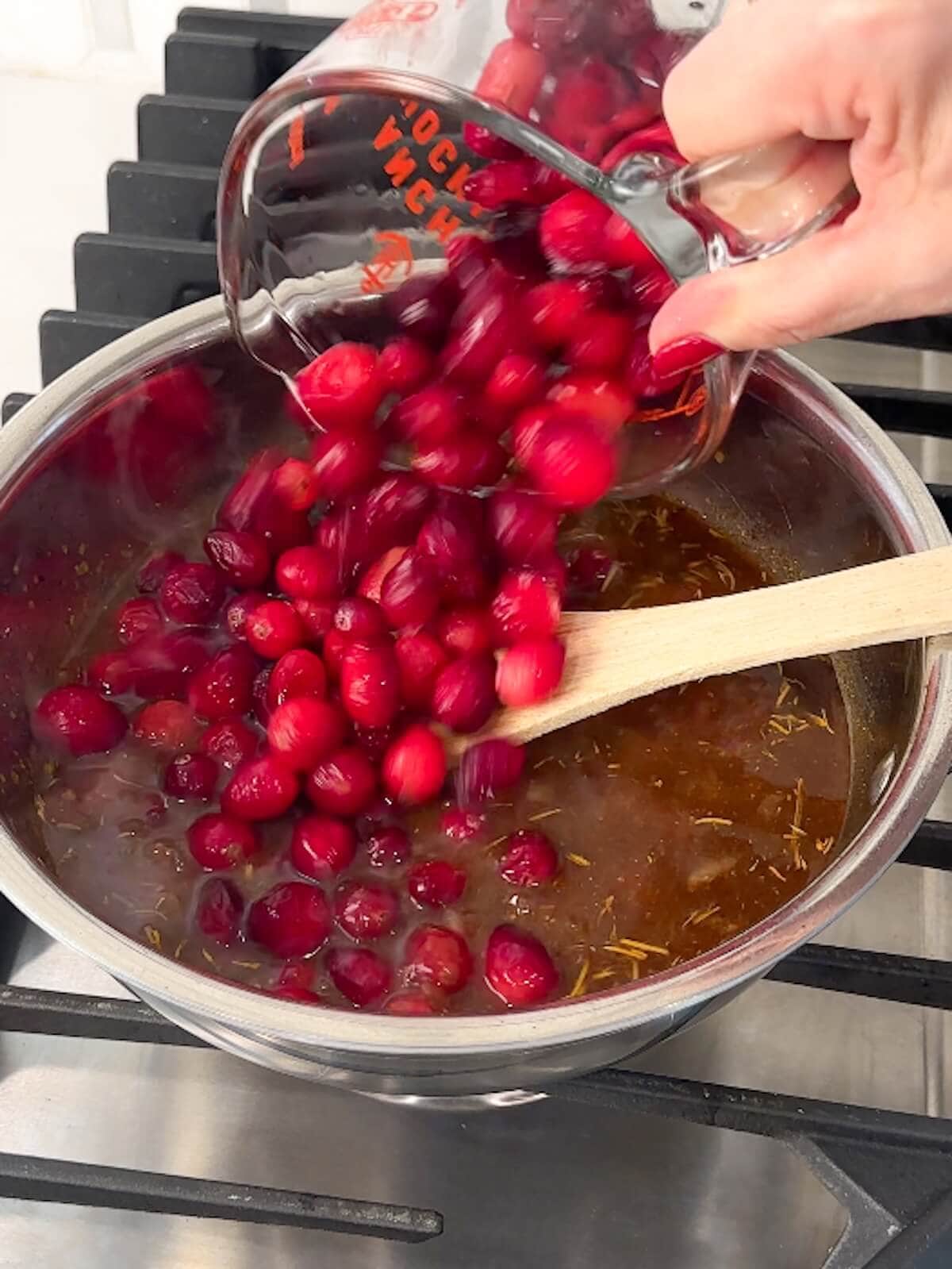 Cranberries being poured into a bowl with other bbq sauce ingredients.