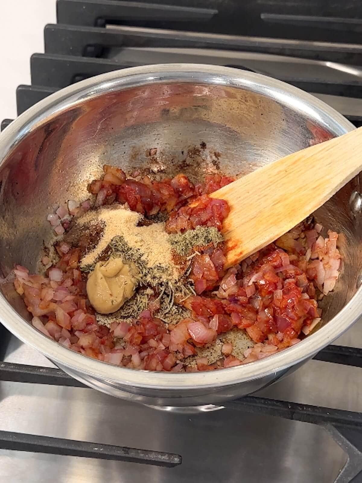 Spices and mustard added to a bowl of other bbq sauce ingredients.