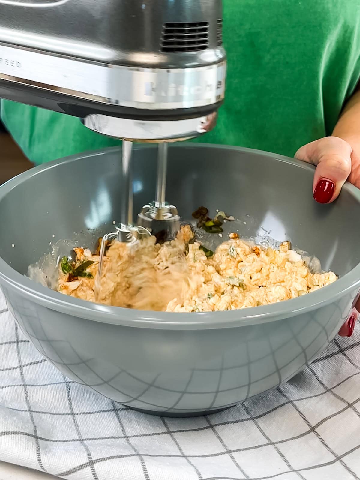 Using a hand mixer to blend together crab dip ingredients.