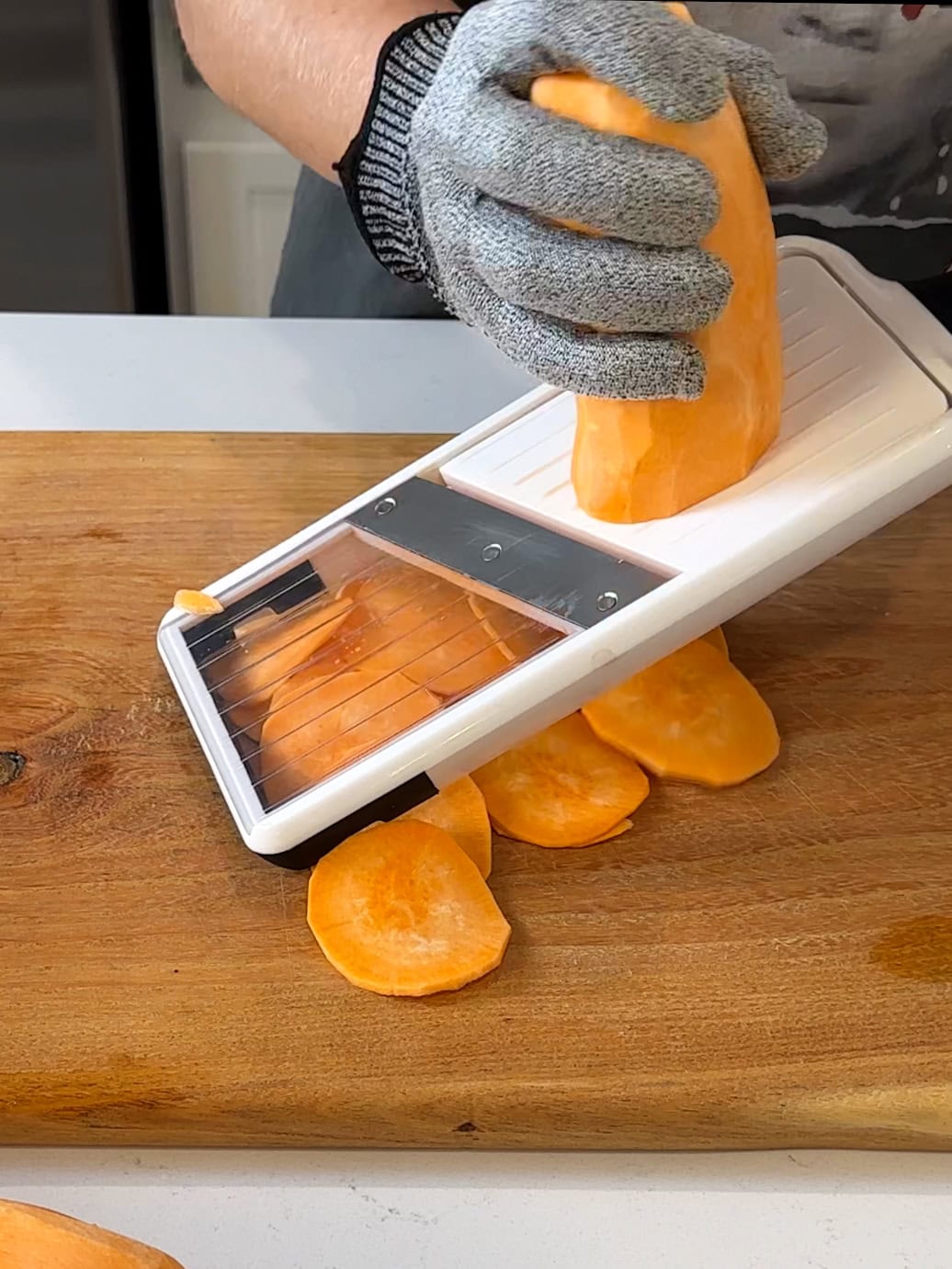 Slicing a sweet potato on a mandolin.