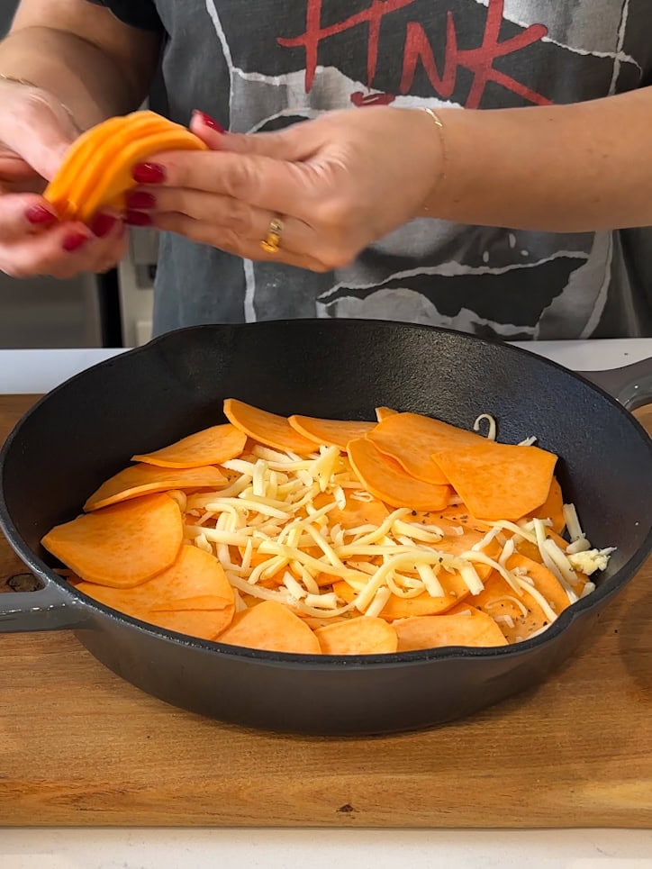 Layering sweet potatoes over spices and cheese.