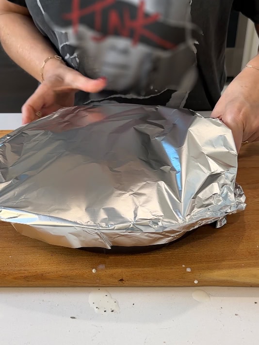 Wrapping the top of a baking dish with tinfoil.