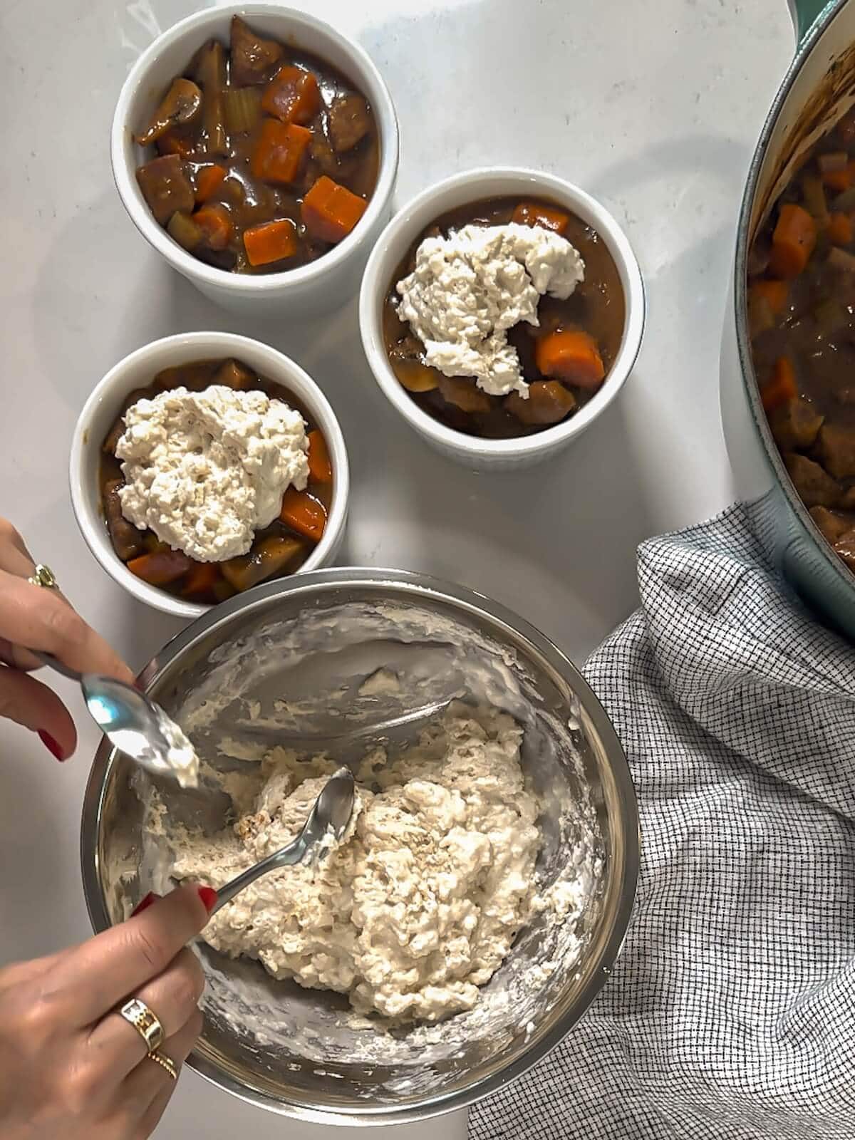 Topping beef stew with biscuit batter before baking.