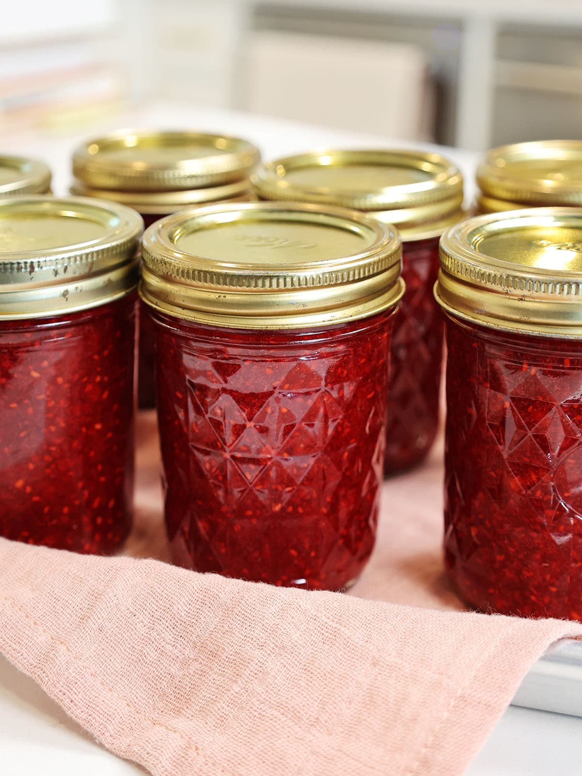 Several jars of raspberry freezer jam with lids on them.
