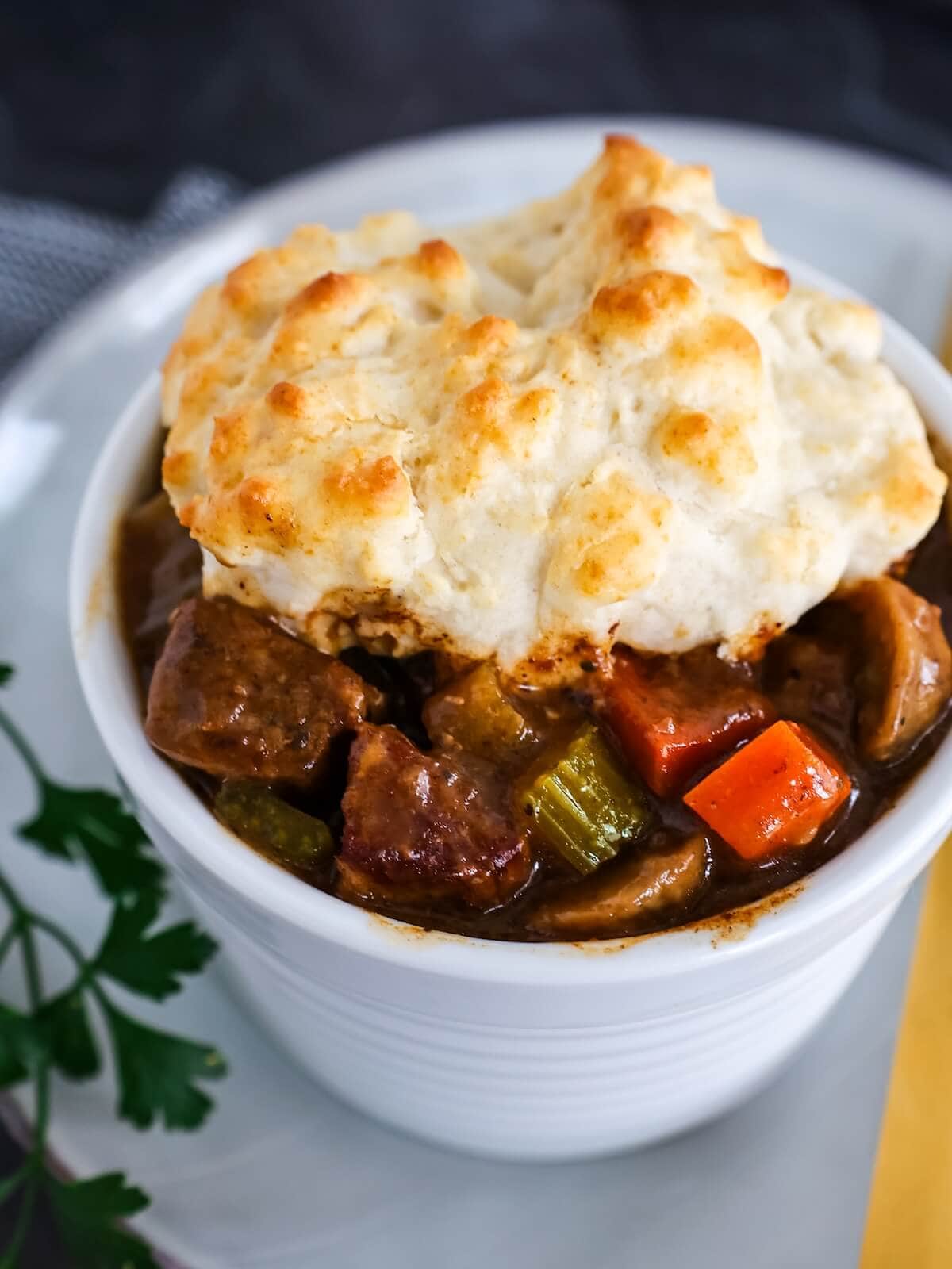 Close up of a bowl of beef stew with biscuit topping.
