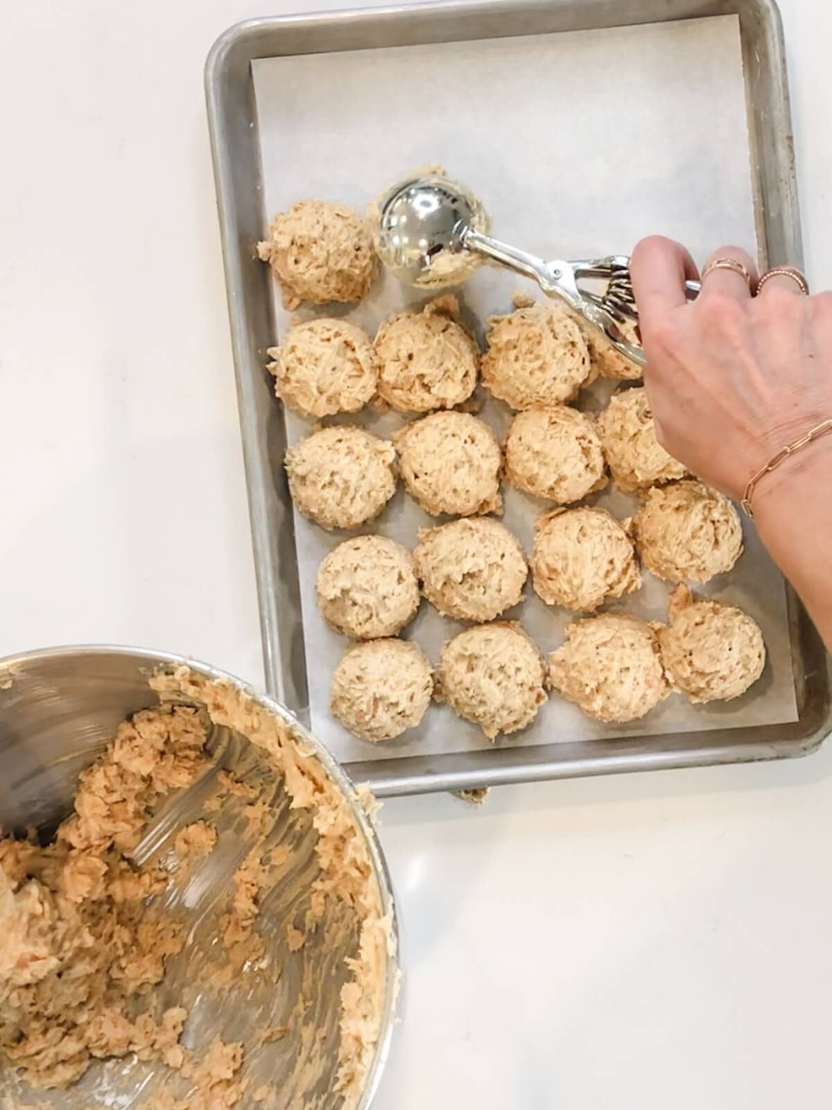 scooping cookie dough with a cookie scoop onto a parchment lined pan.
