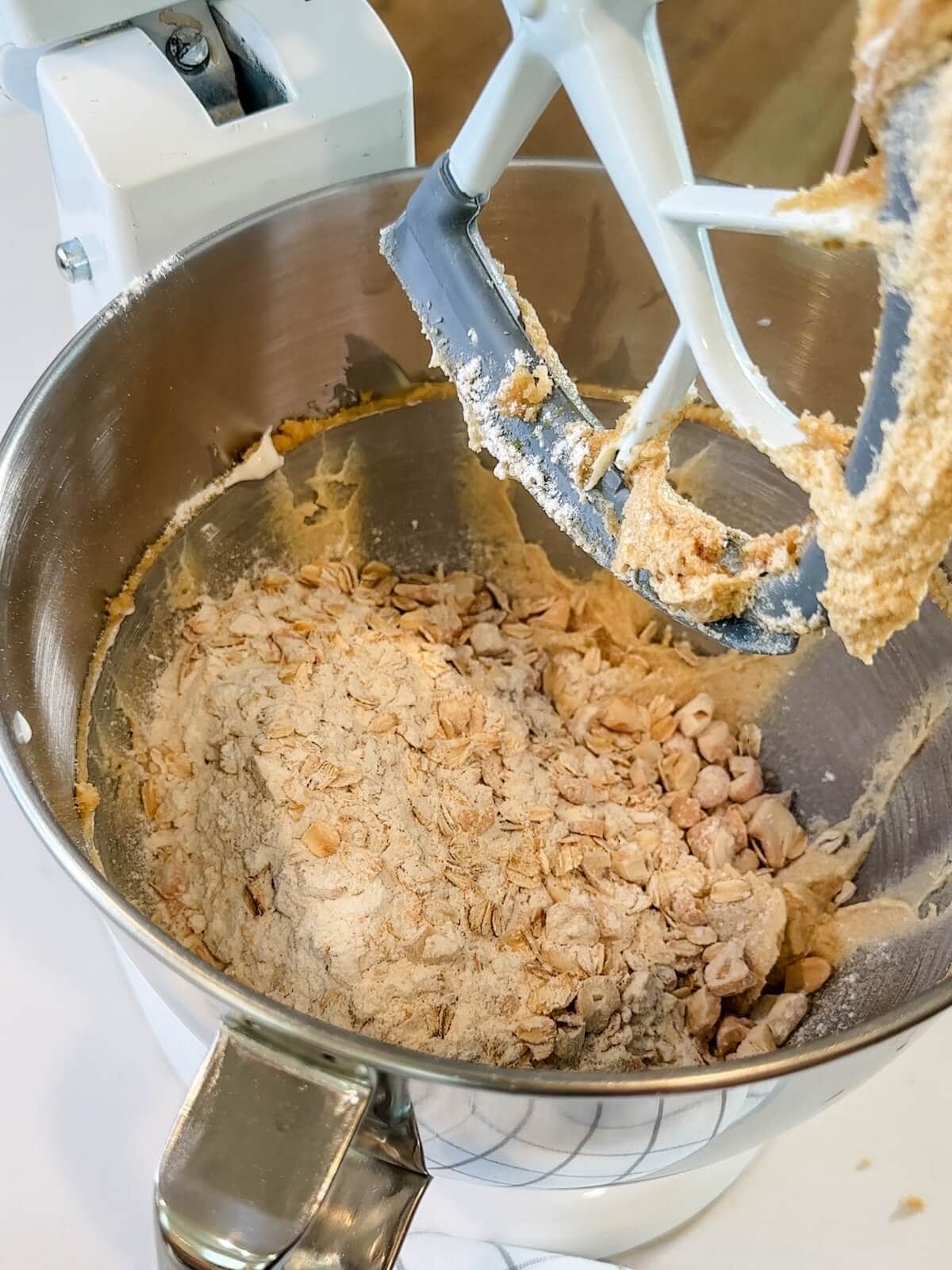 adding dry ingredients, oats, and cashews to cookie batter to mix.
