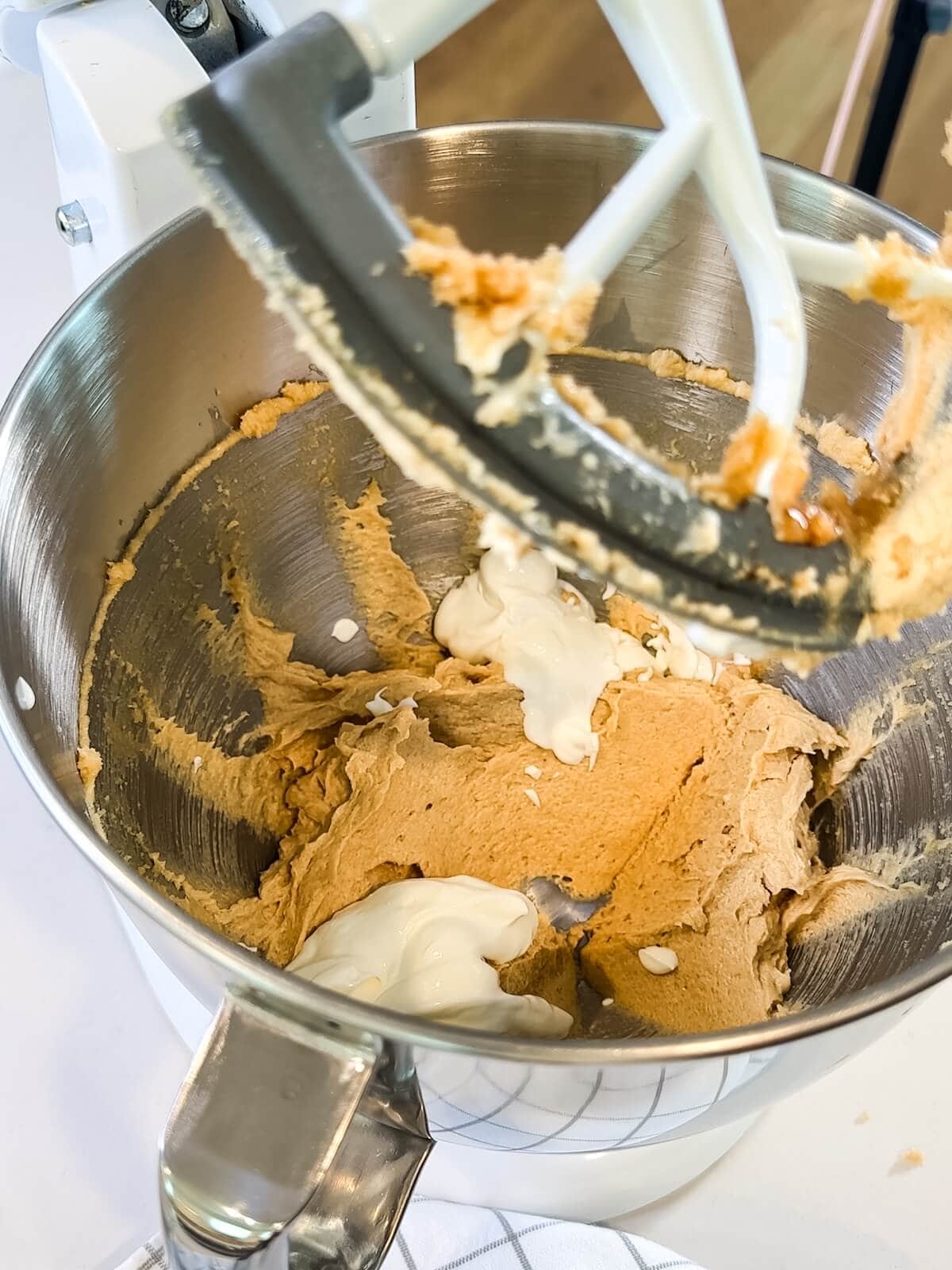 adding sour cream to cookie batter in a mixing bowl.