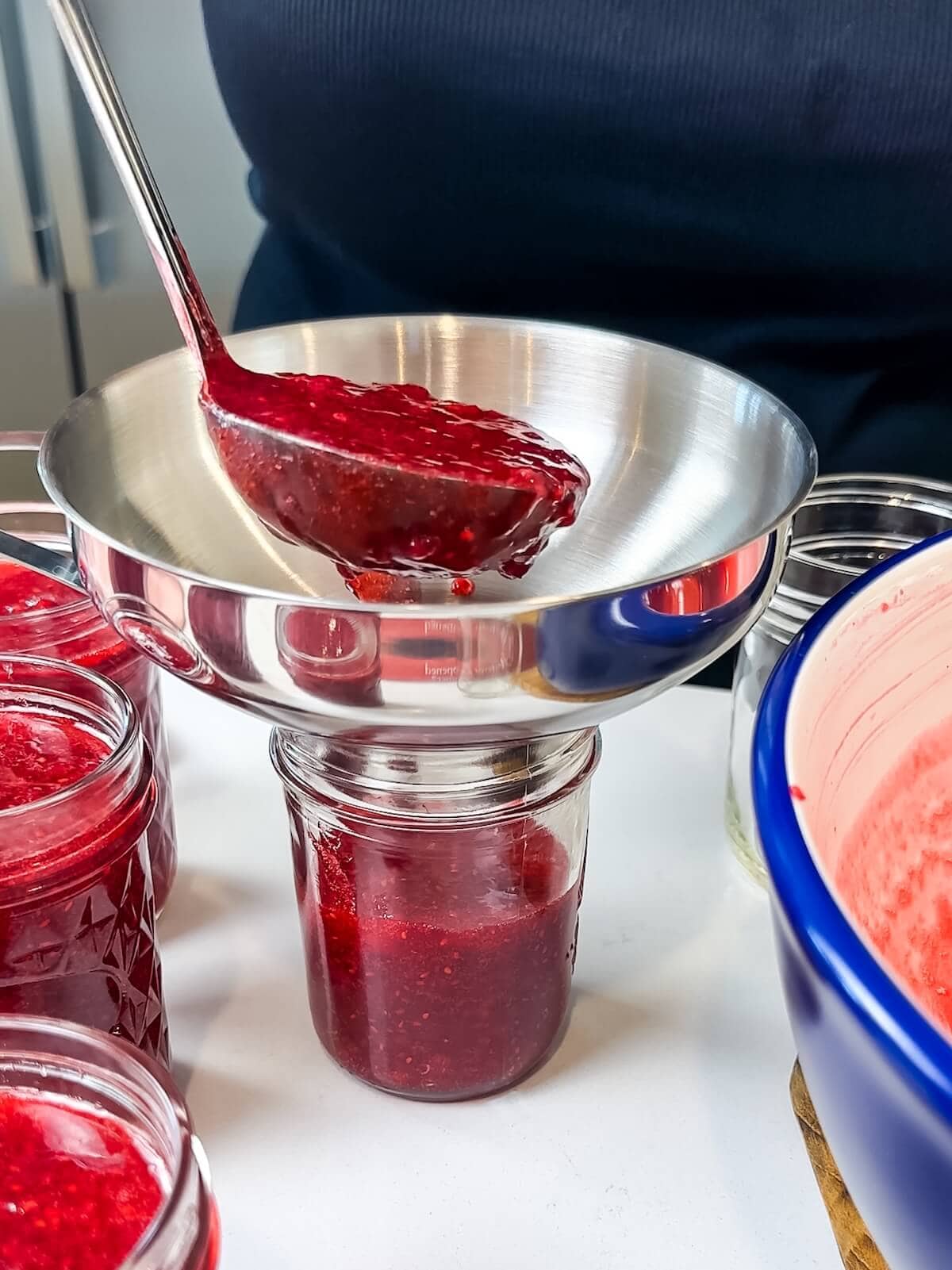 filling jars with jam using a jar funnel and ladle.