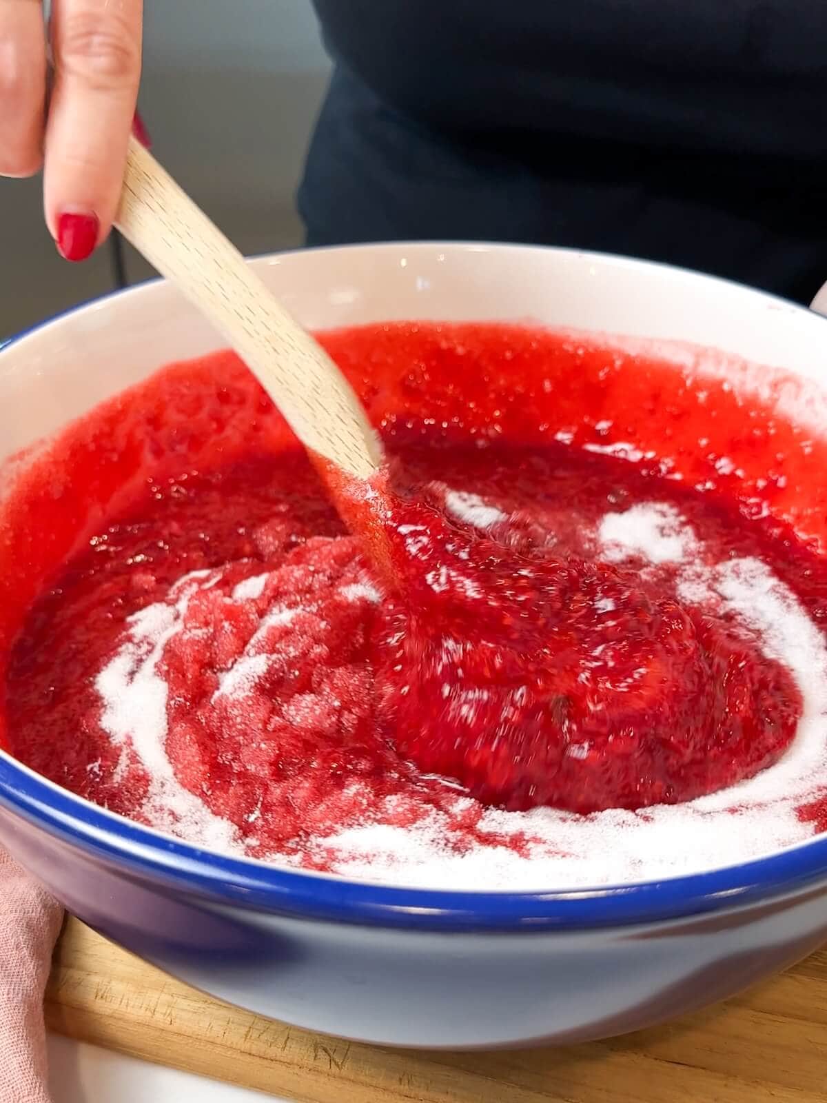 stirring sugar in in batches to raspberry jam.