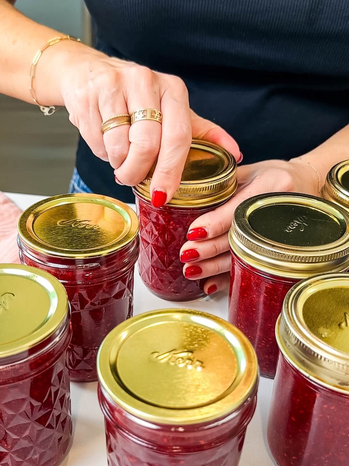 adding lids to raspberry jam bottles to store.