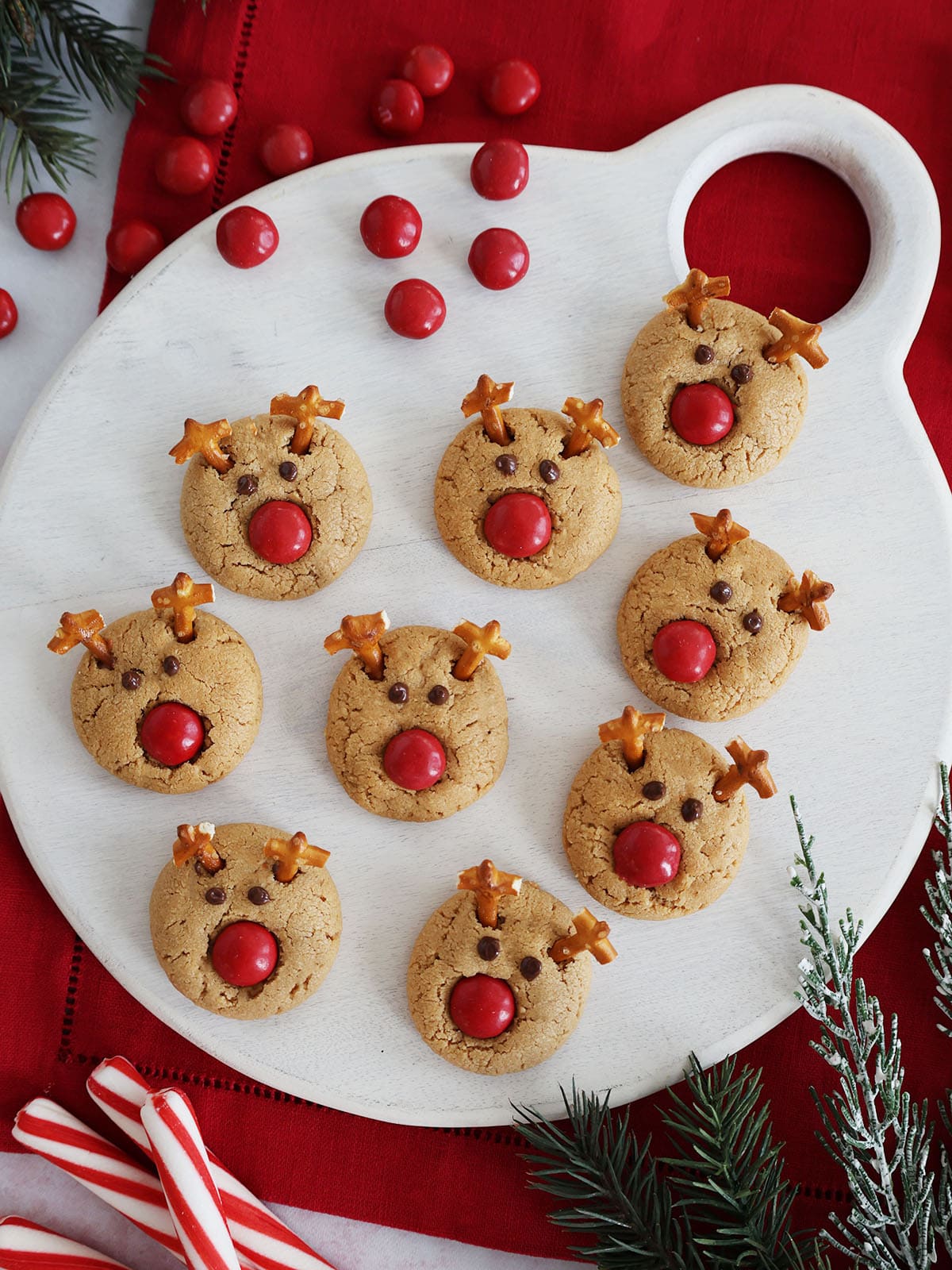 Top view of Rudolph reindeer cookies on a white cutting board.