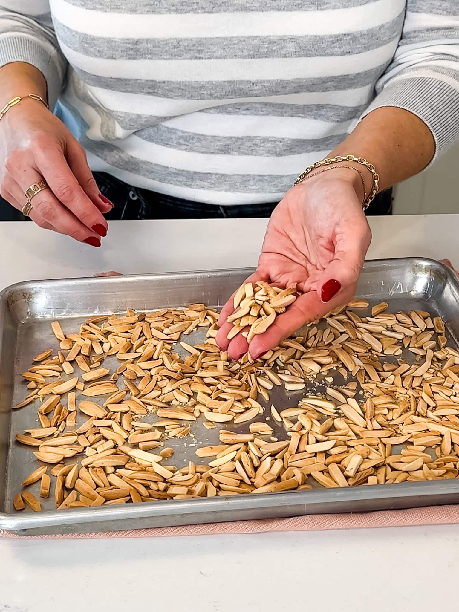 Slivered almonds spread in a single layer on a baking sheet for toasting.