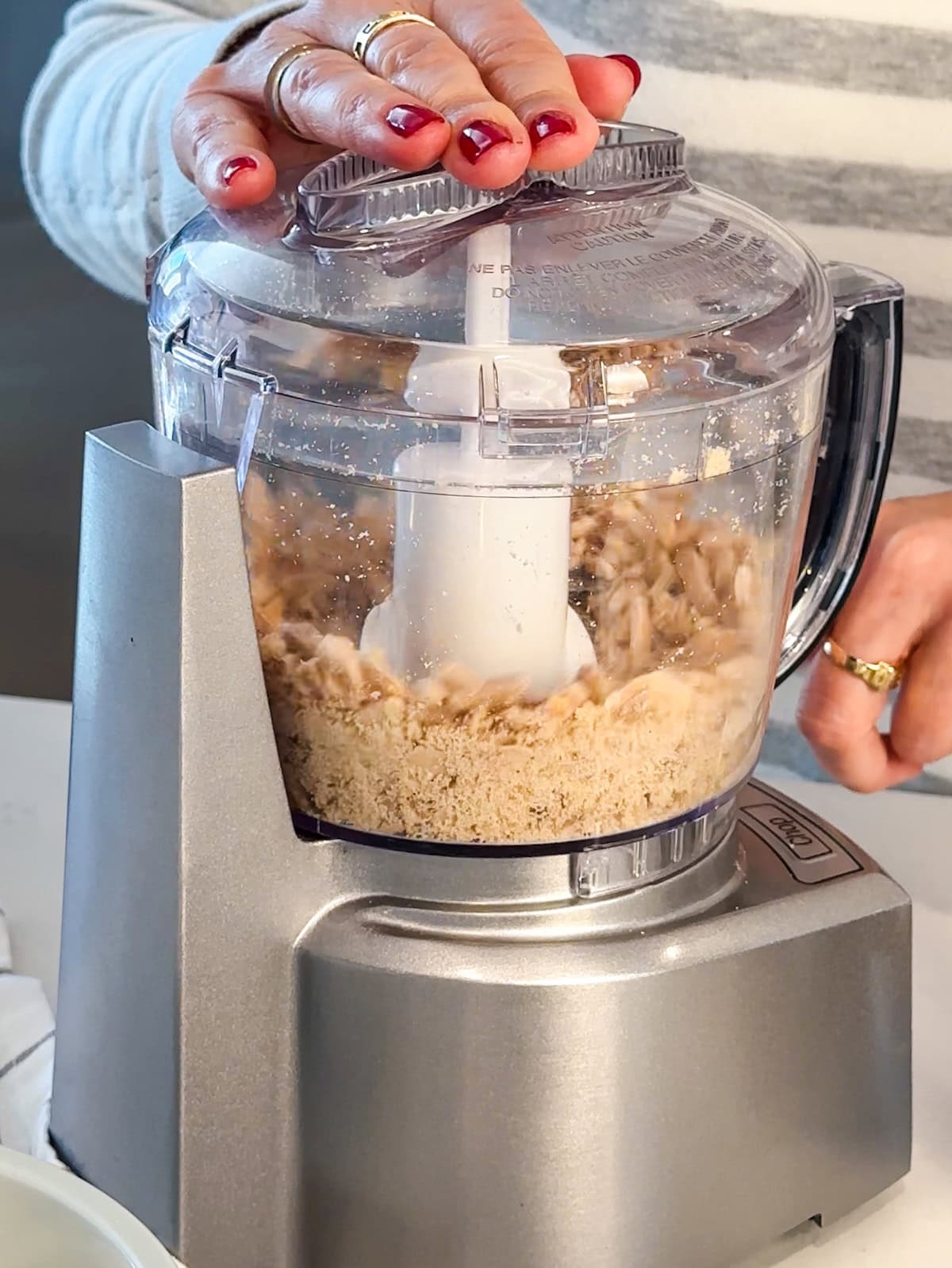 Using a food processor to finely chop toasted almonds.