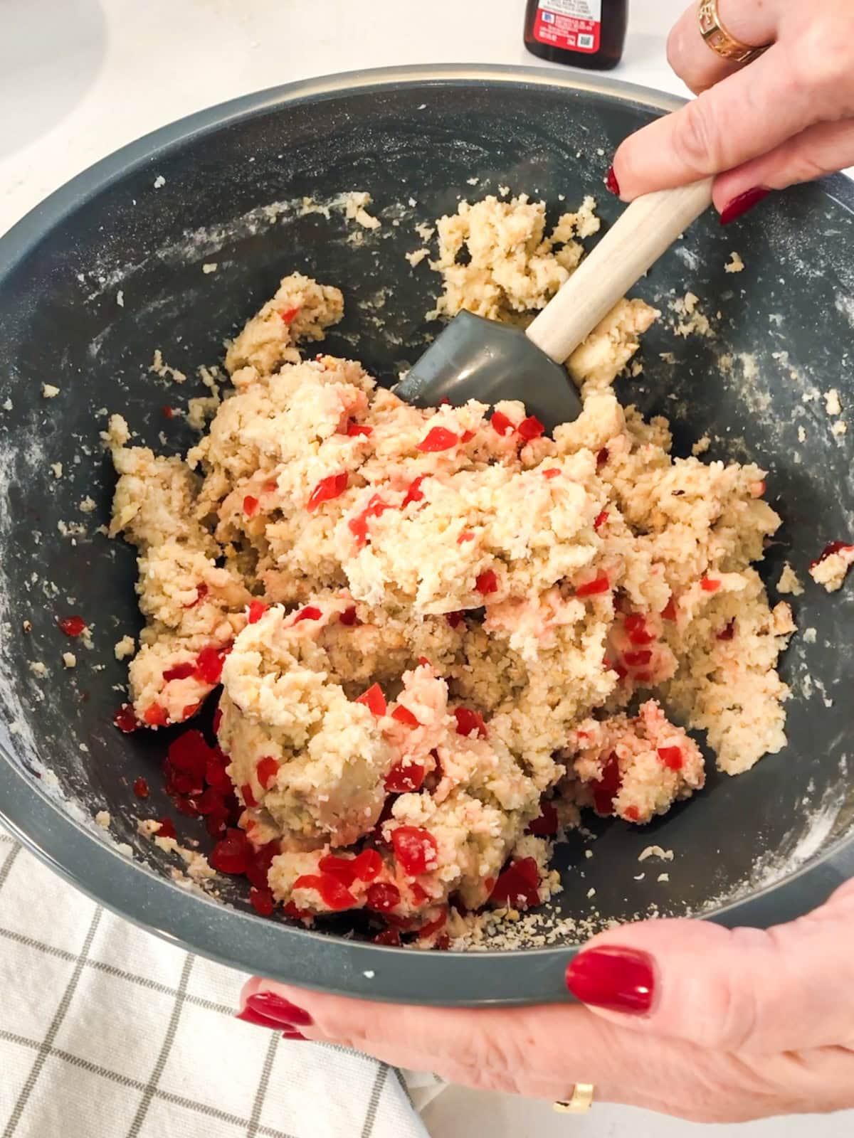 Hand mixing a bowl of cherry almond cookie dough.