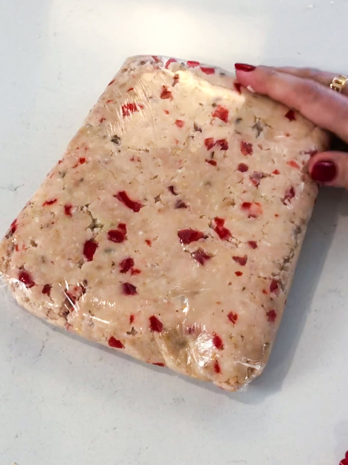 Cherry almond cookie dough wrapped in plastic wrap.