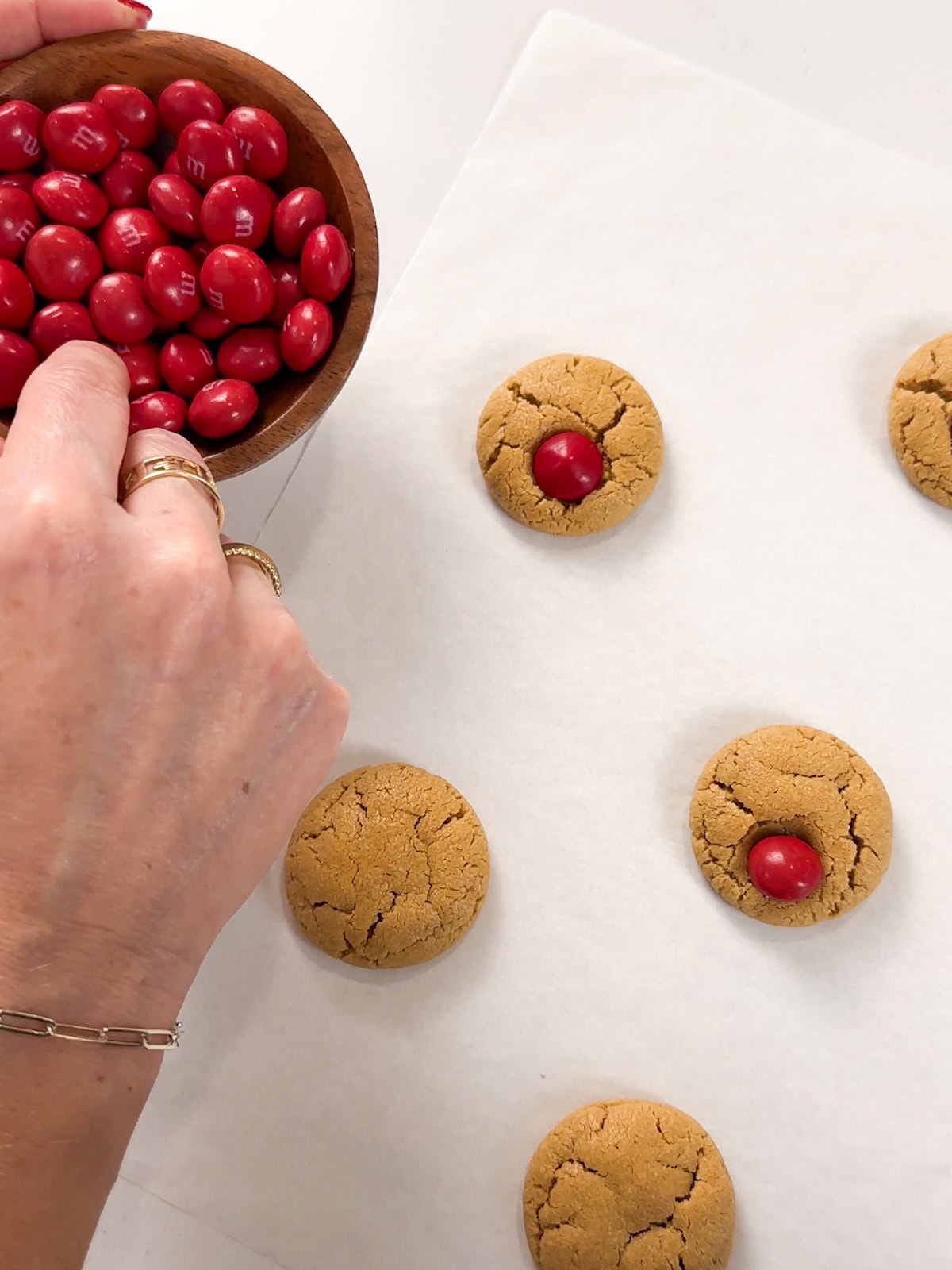Right out of the oven place a red peanut butter m&m on each peanut butter cookie.