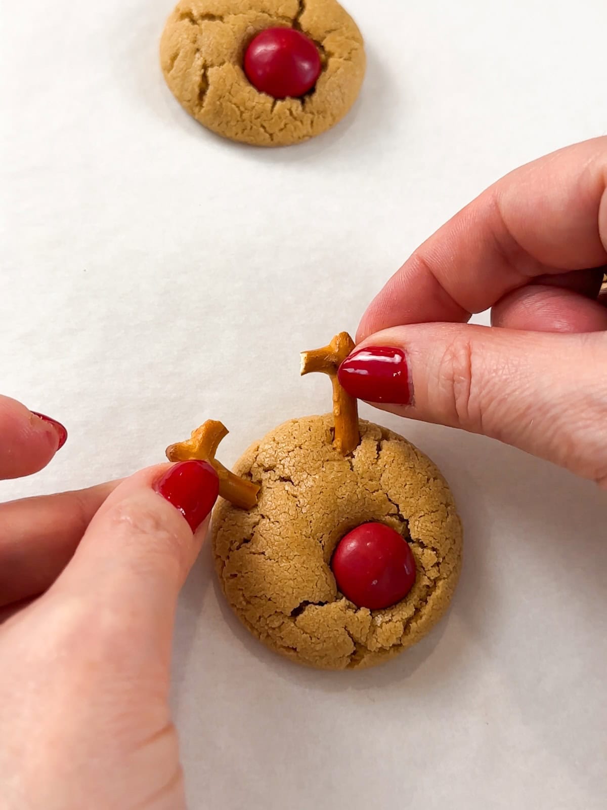 Add pretzel antlers to the peanut butter cookies while still warm.