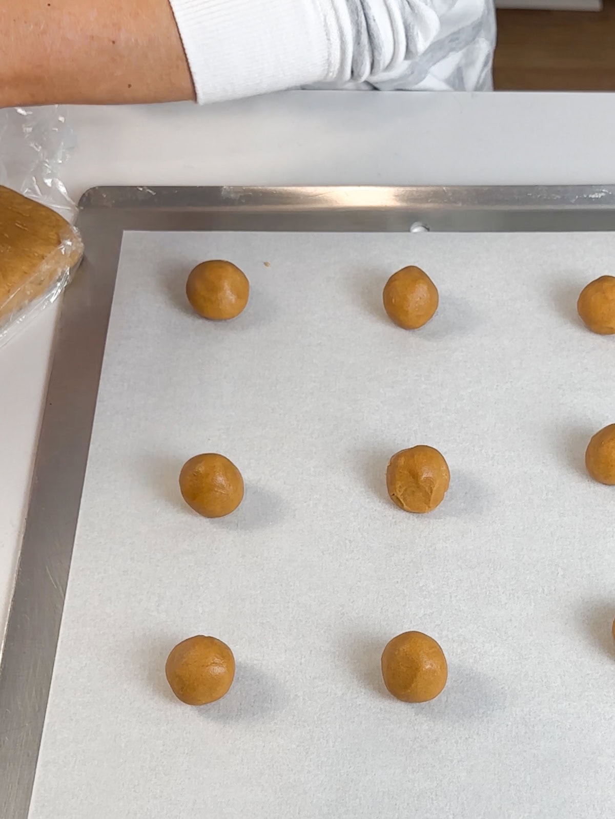 roll small balls of peanut butter cookie dough and place on parchment lined baking sheets to cook.
