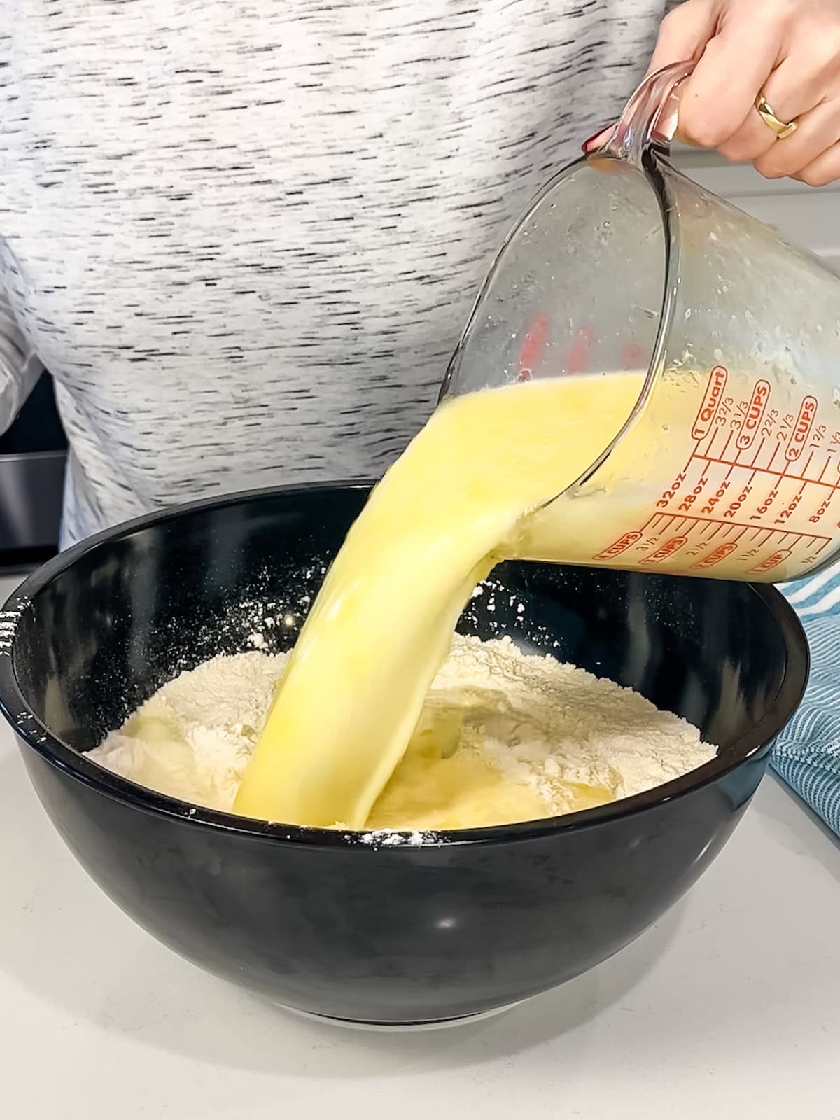 adding liquid ingredients to dry ingredients to make soft cornbread.