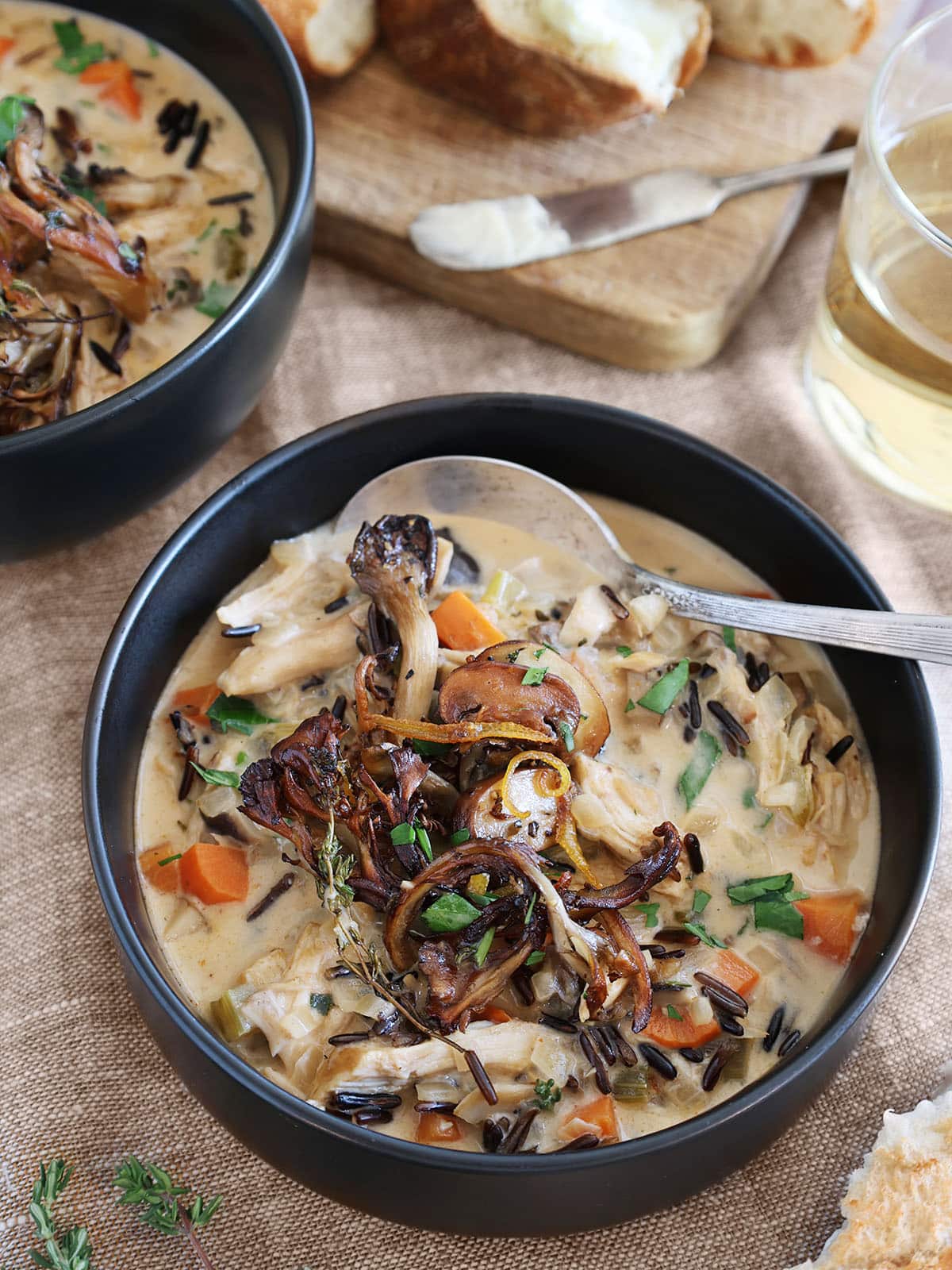 A bowl of chicken mushroom soup with a silver spoon in it.