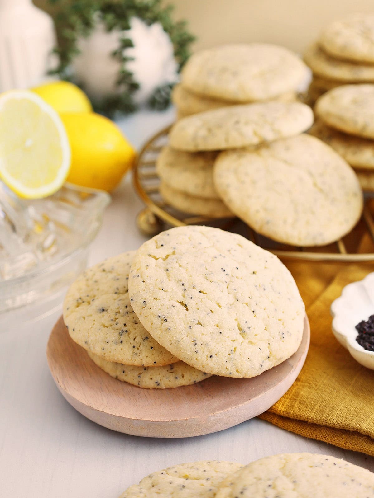 Three lemon poppyseed cookies piled on a small wooden plate.