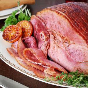 Close up of a glazed ham on a white platter.
