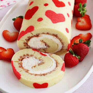 Close up of a Valentine's Day strawberry cake roll with a slice cut off the end.