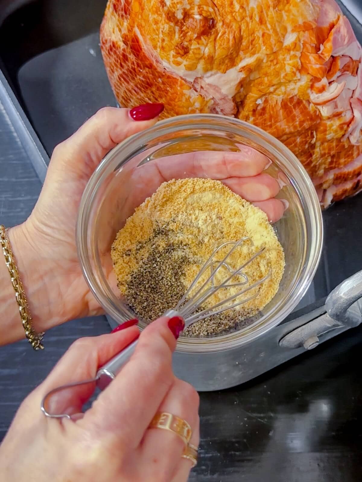 Hand mixing spice rub for ham. in a small glass bowl.