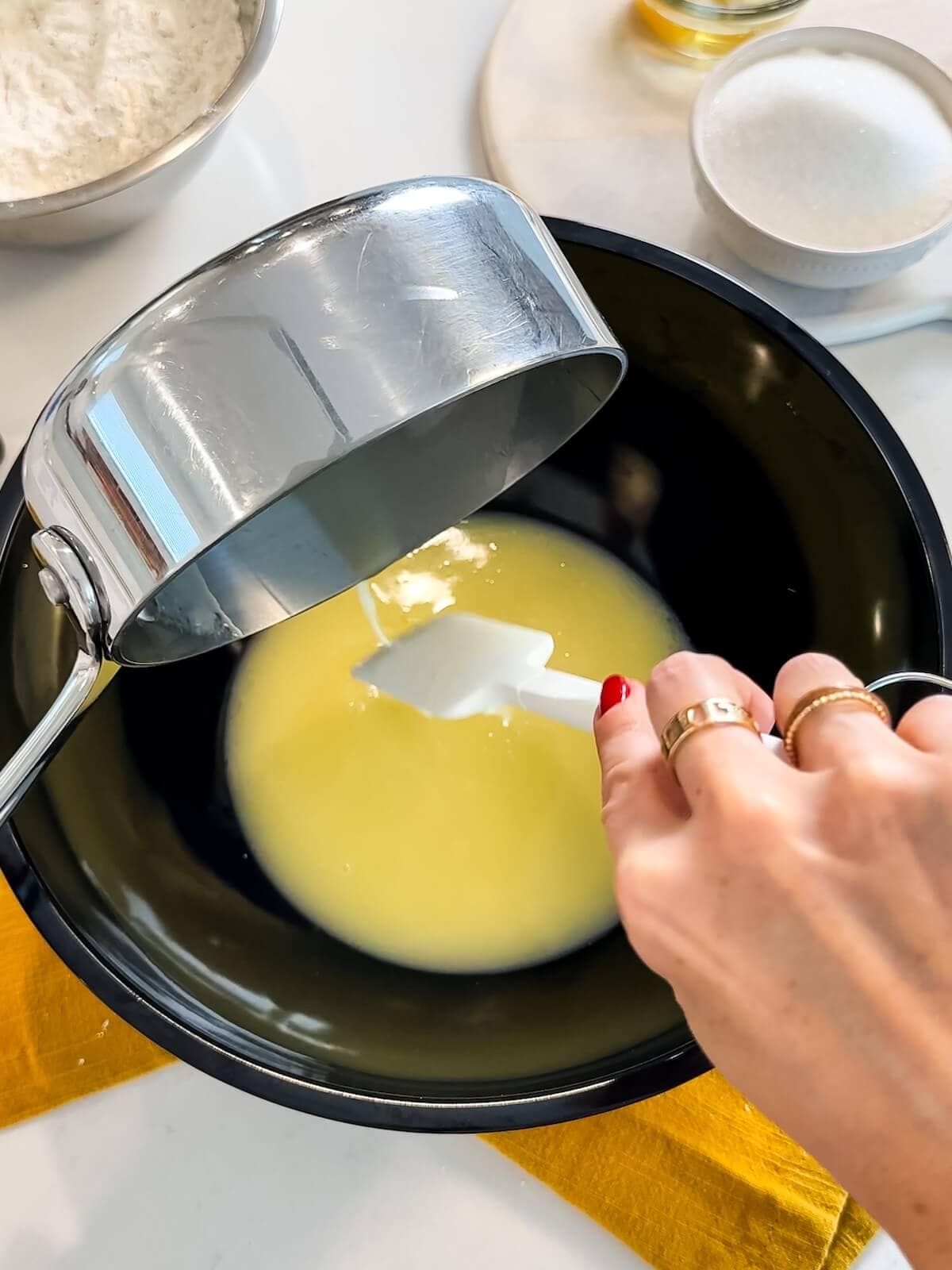 Adding cooled butter and lemon juice mixture to a mixing bowl.
